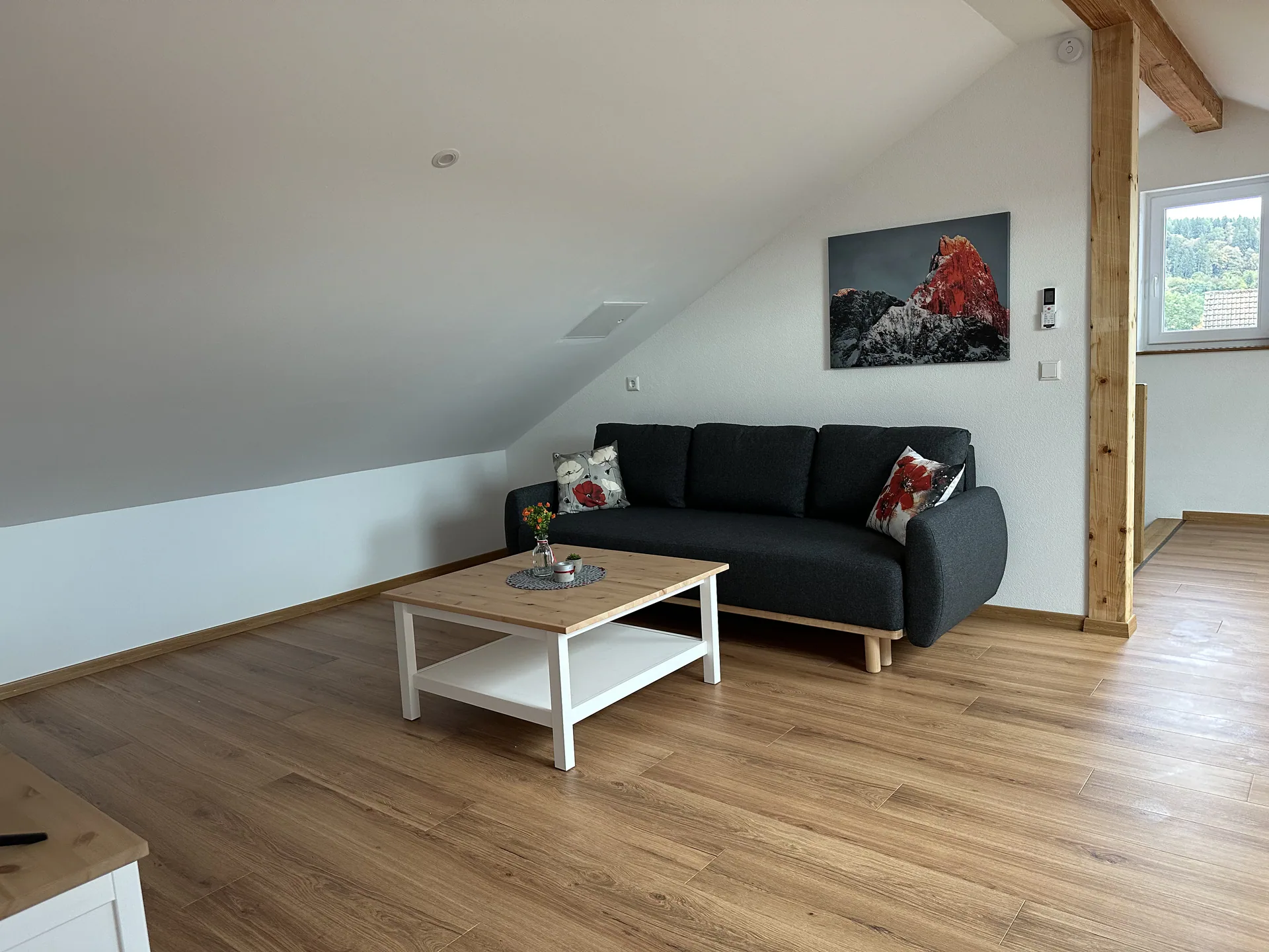 Großzügiger Dachwohnraum der Maisonette-Wohnung in Balzheim mit Sofa und sichtbaren Holzbalken