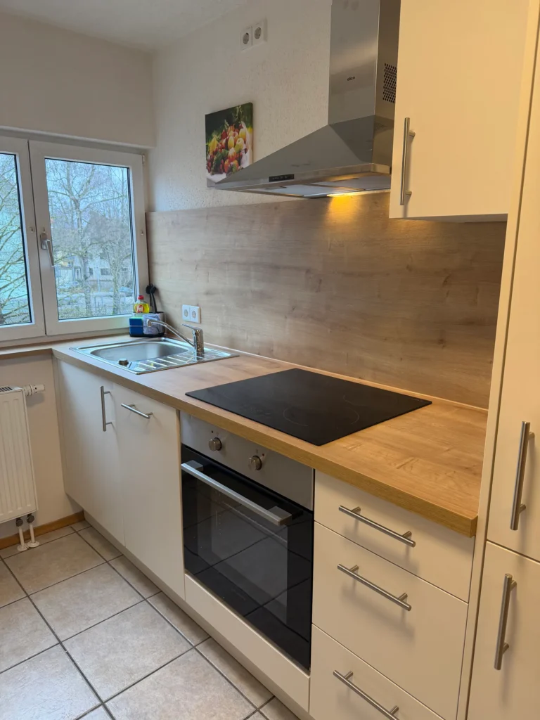 Moderne Einbauküche mit Holzarbeitsplatte und Kochfeld in der Ferienwohnung Memmingen
