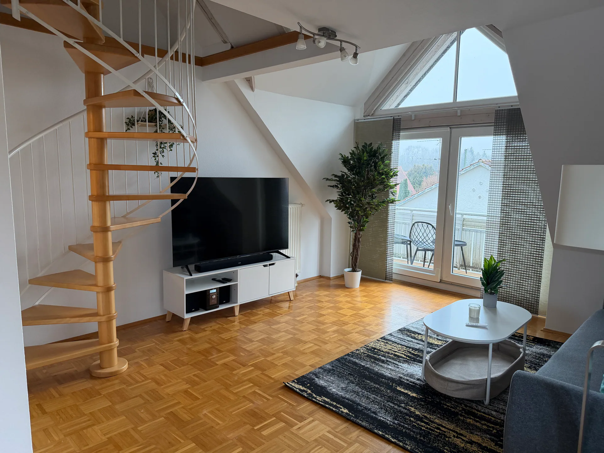 Heller Wohnbereich der Maisonette-Wohnung in Memmingen mit Wendeltreppe, Balkon und hoher Fensterfront