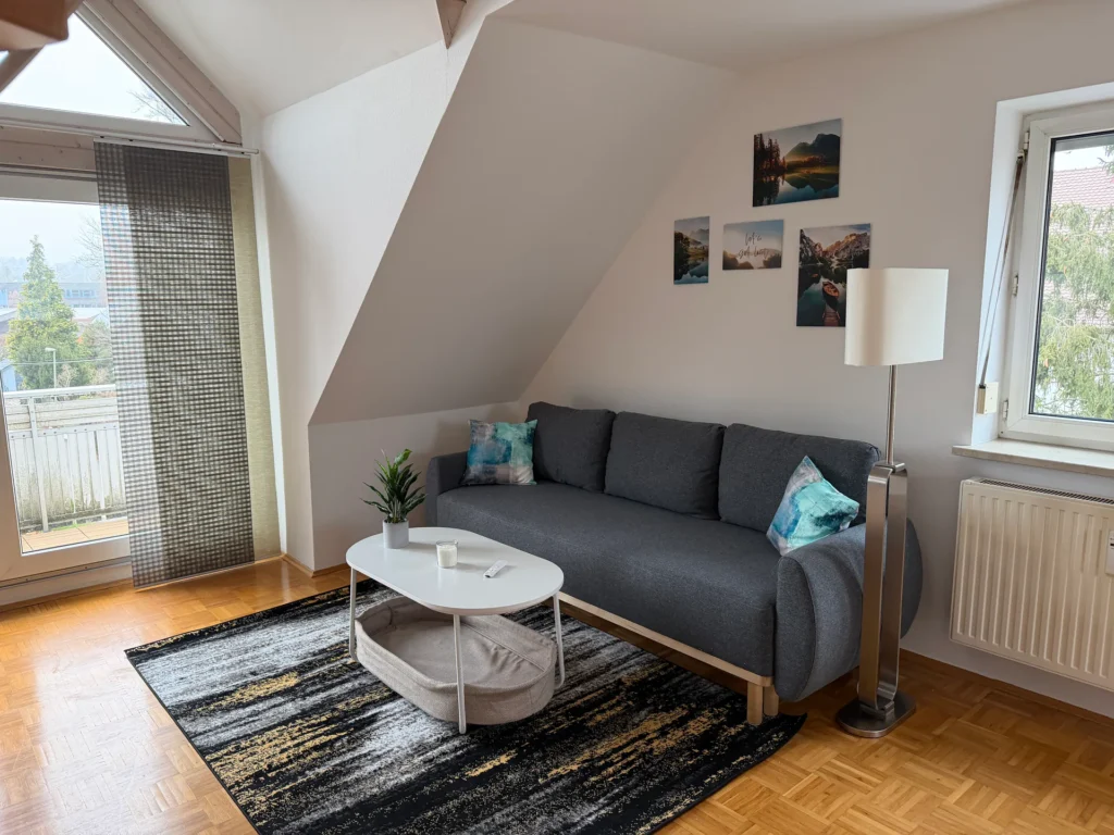 Gemütlicher Wohnbereich mit Sofa und Zugang zum Balkon in Memmingen